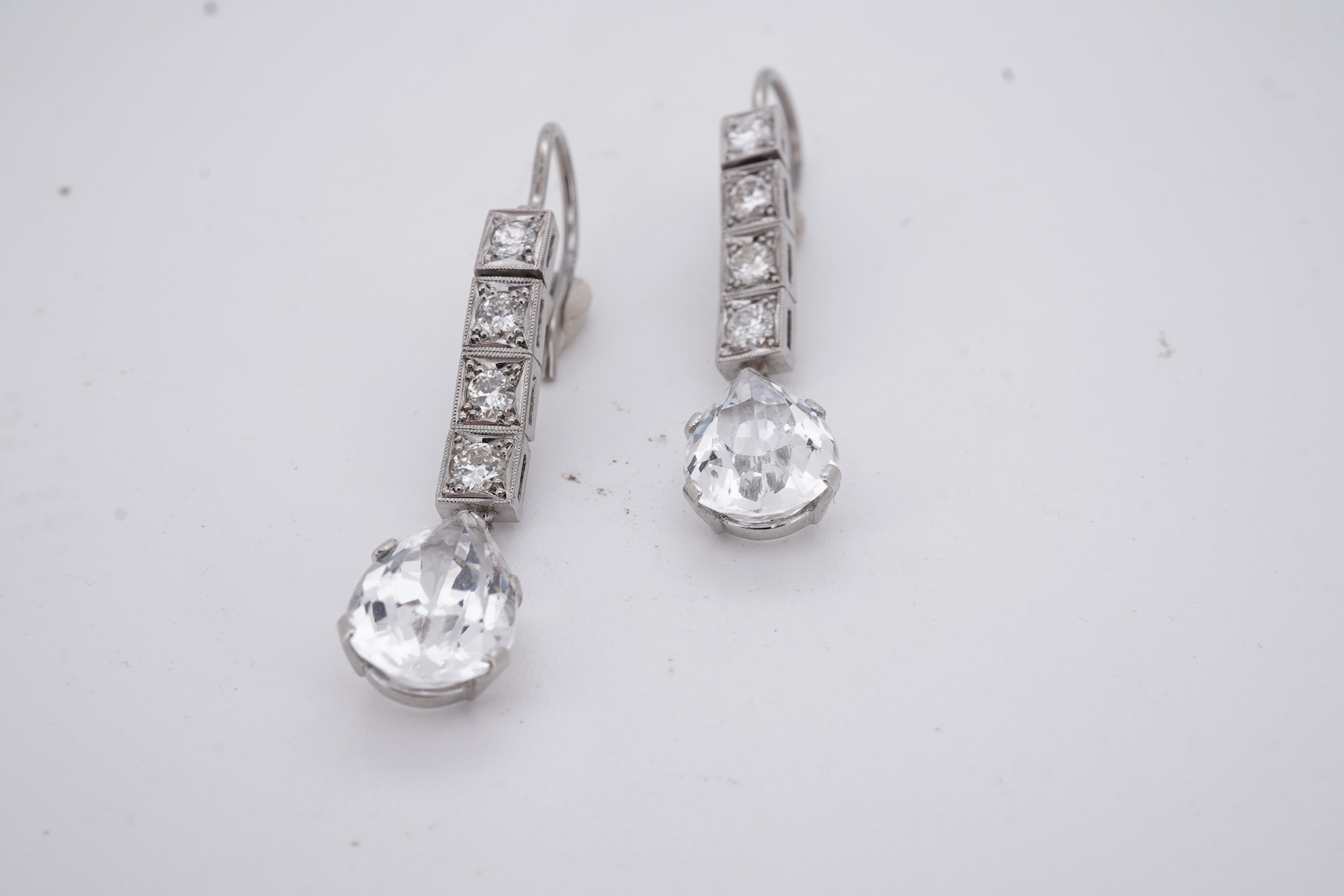 A pair of white metal and four stone diamond set earrings, each with a cubic zirconia pear shaped drop, overall 42mm.
